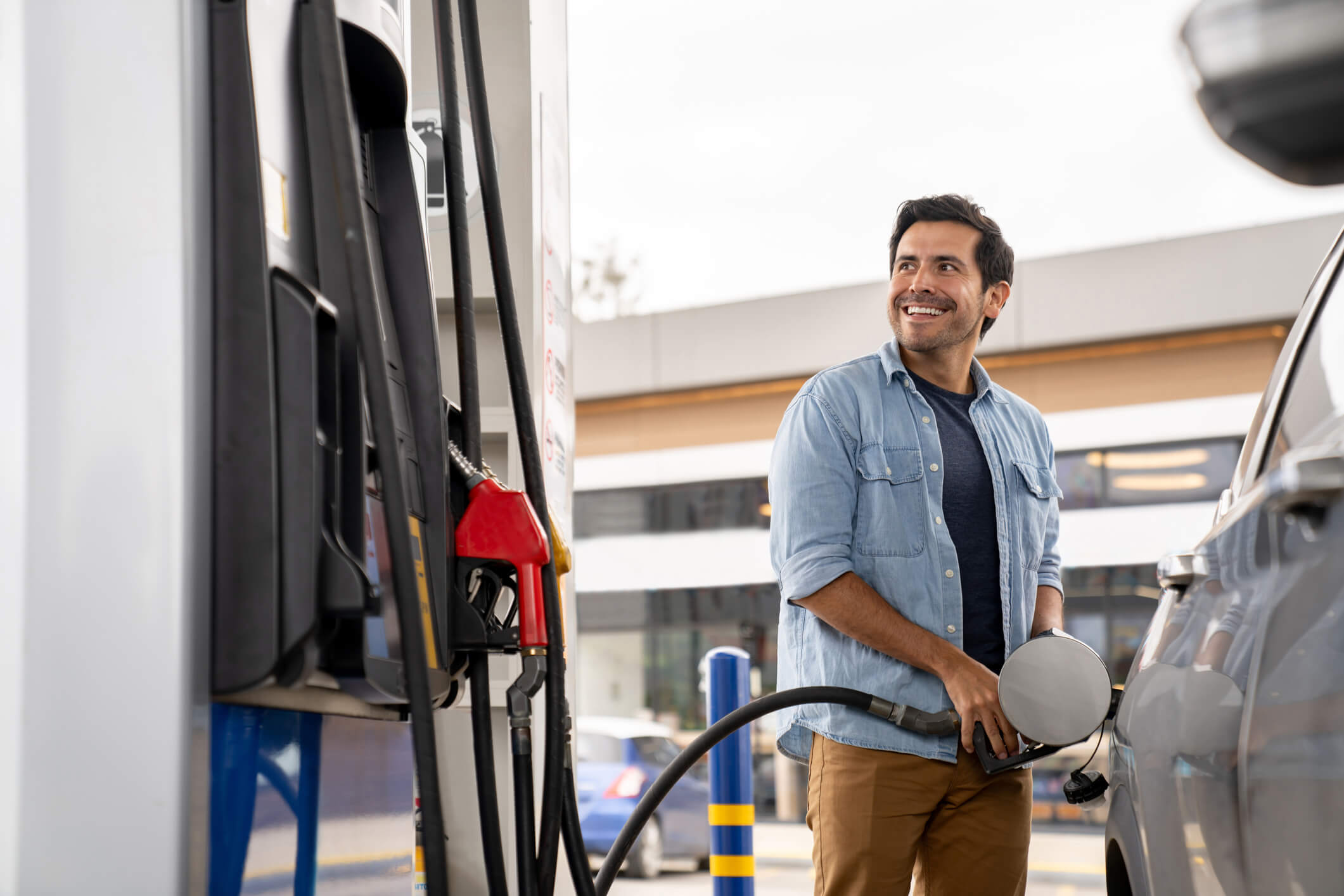 Happy man putting gas in his car at a petrol station